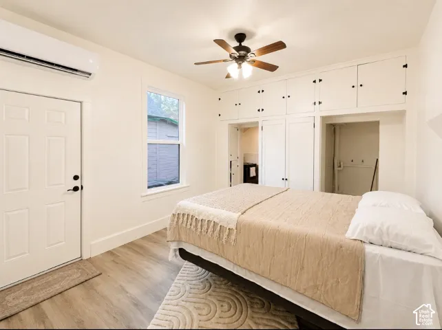 Unit 1 bedroom. Room featuring wood-finish flooring, built-in cabinetry, a ceiling fan with integrated lighting, and a single window