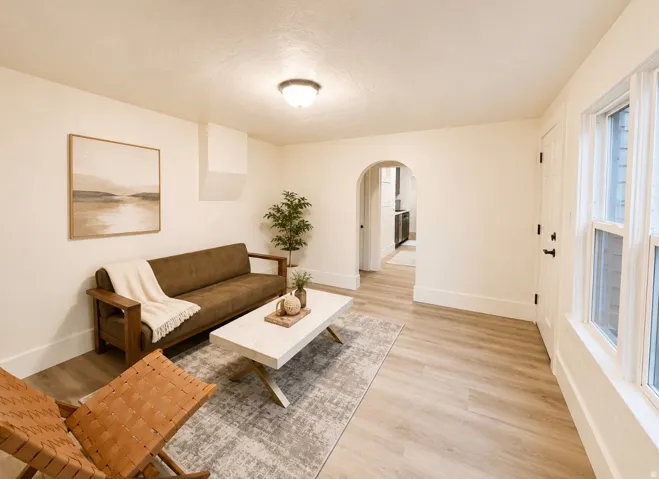 Unit 2 living room featuring wood-finish flooring, white baseboards, and an arched doorway