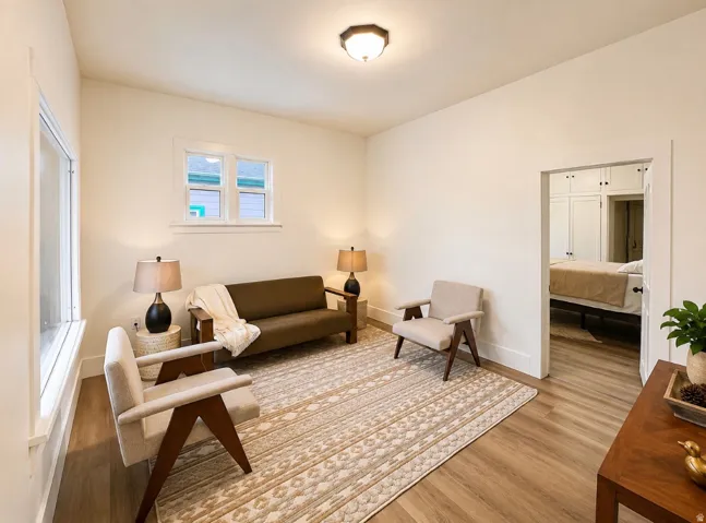Unit 1 living room. Bright interior space featuring light-toned walls and wood-finish flooring