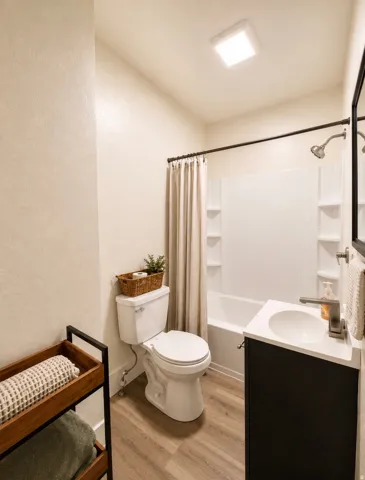 Unit 2 Full bathroom with a white tub-shower combination, dark vanity, and wood-finish flooring