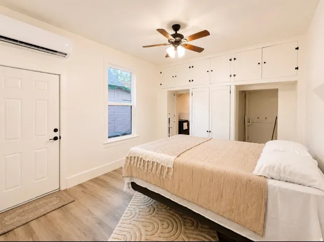 Unit 1 bedroom. Room featuring wood-finish flooring, built-in cabinetry, a ceiling fan with integrated lighting, and a single window