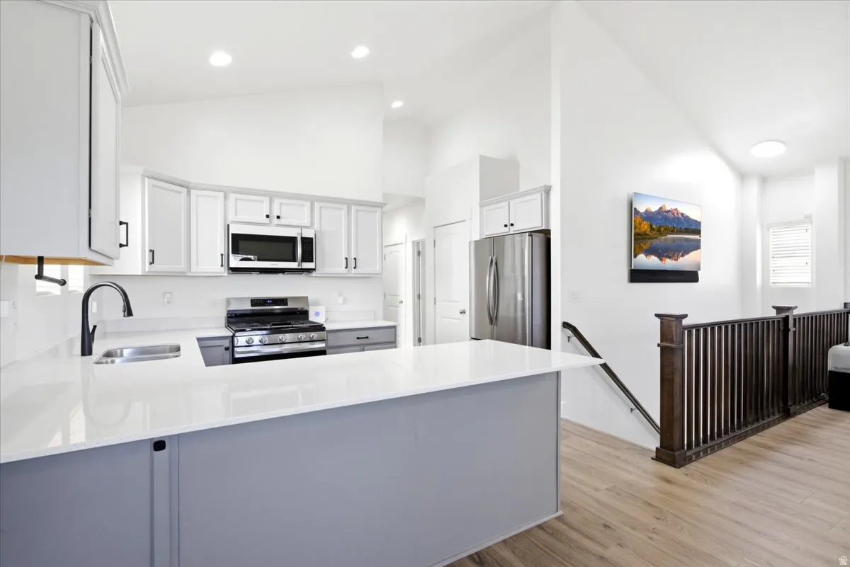 Modern kitchen featuring white cabinetry, stainless steel appliances, a gas range, and a spacious island with a light-colored countertop
