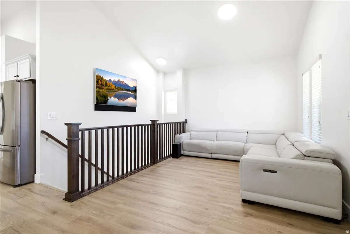 Upper level lounge area featuring vaulted ceilings, wood-finish flooring, and dark wood railings