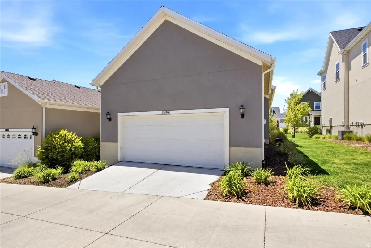 Attached two-car garage with a concrete driveway and modern wall sconces