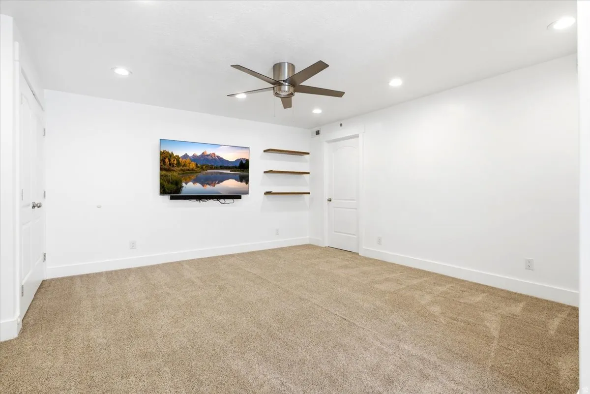 Spacious room featuring neutral carpeting, white walls, recessed lighting, and a contemporary ceiling fan