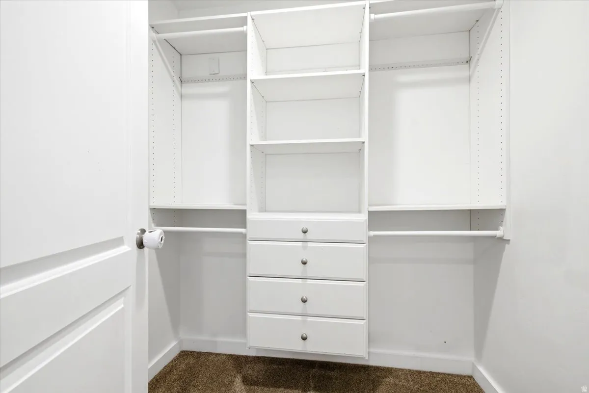 Built-in white custom closet system featuring multiple shelving units, hanging rods, and four integrated drawers with brushed nickel hardware