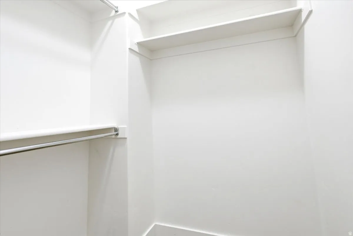 Walk-in closet with white shelving and chrome hanging rods