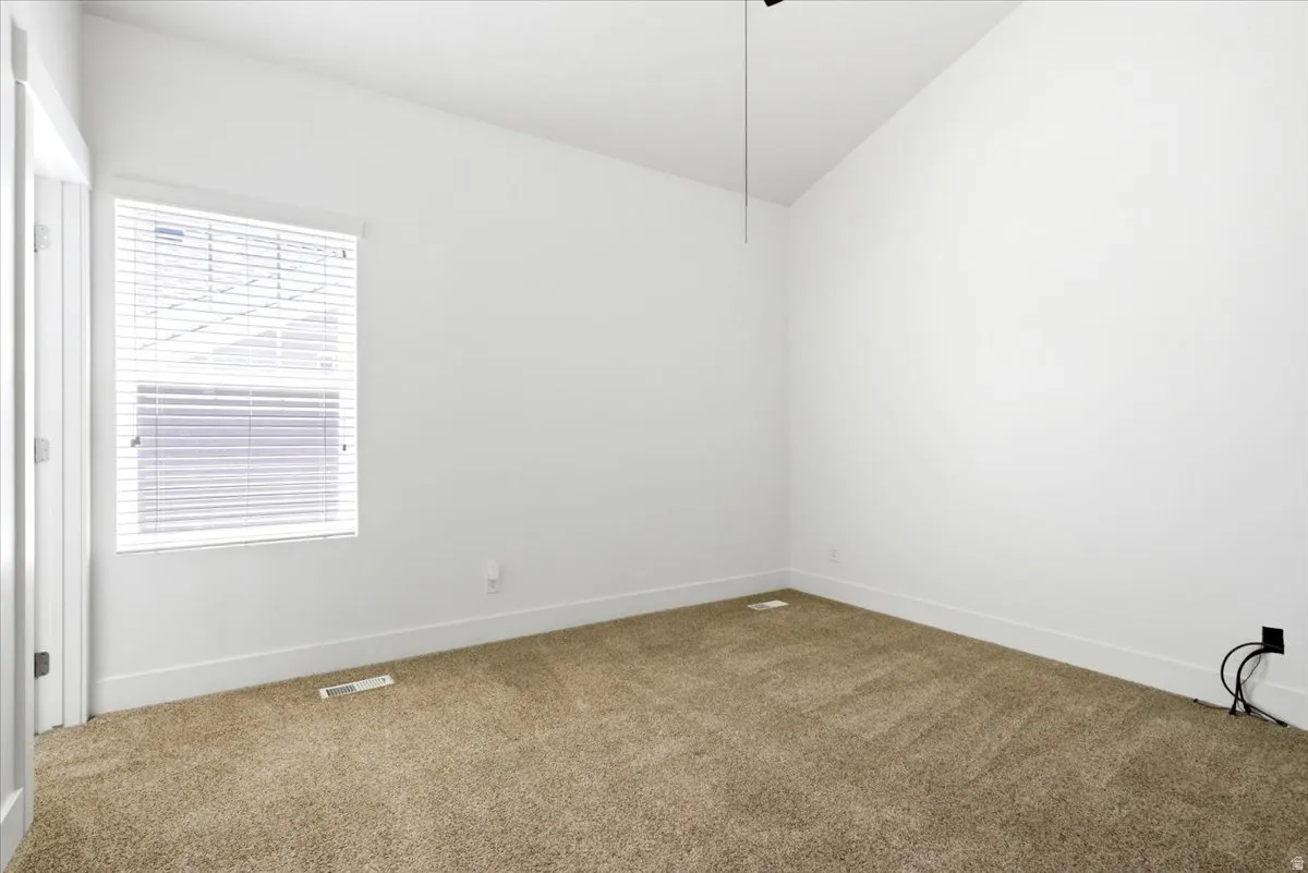 Open room featuring neutral-toned carpet flooring and a vaulted ceiling