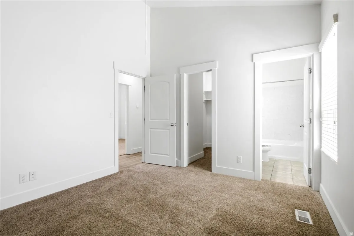 Carpeted room with white walls, baseboards, and door frames