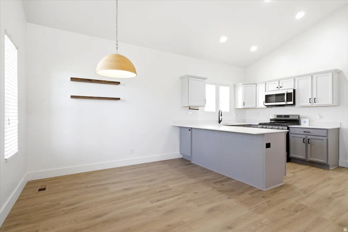 Open-concept kitchen and dining area featuring a vaulted ceiling and wood-finish flooring