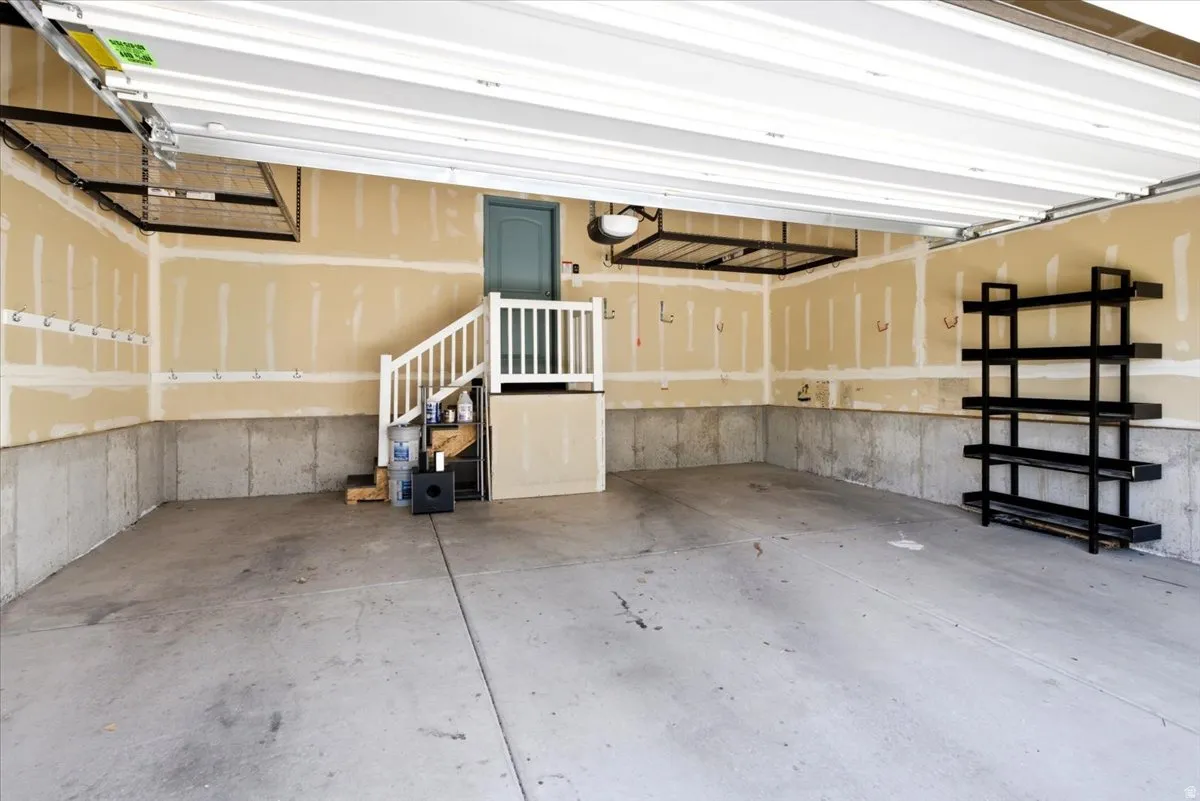Spacious garage featuring a finished concrete floor, unfinished walls, overhead storage racks, a built-in shelving unit, and an interior access door