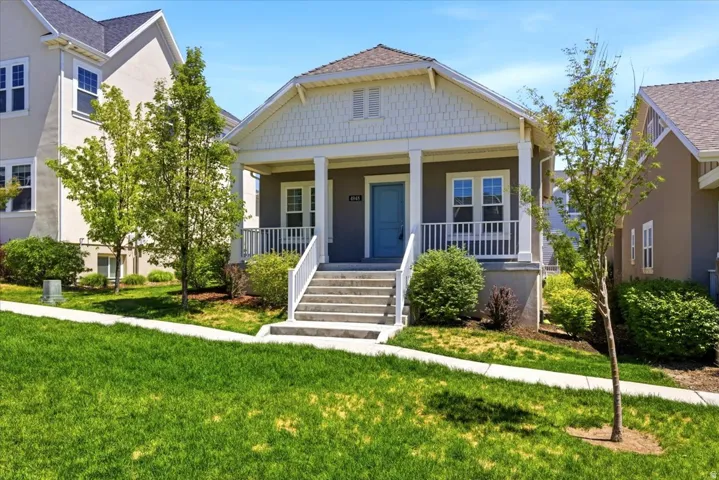 Contemporary bungalow-style residence featuring a prominent front porch, concrete steps, and white railing