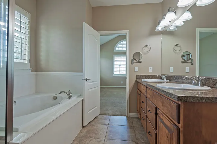 Bathroom featuring a double vanity with wood-finish cabinetry, a large mirror, and individual basin sinks