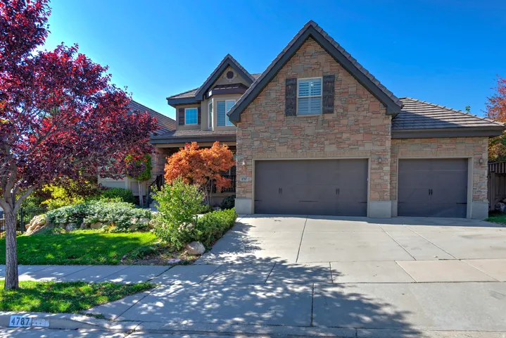 Stone facade home featuring a two-car garage, an additional single-car garage, and a concrete driveway