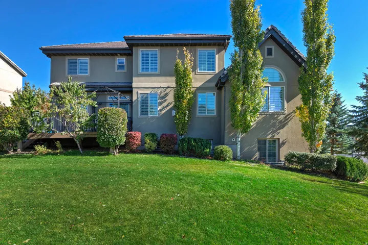 Rear exterior featuring a stucco facade, wood-finish decking, and a walk-out basement