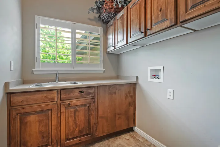 Laundry room featuring wood cabinetry, a utility sink, and ample counter space
