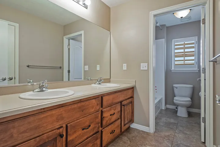 Dual vanity with wood-finish cabinetry, light-toned countertop, and undermount sinks