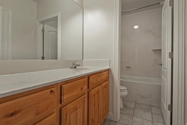 Bathroom featuring a wood-finish vanity with a light-toned countertop, an integrated sink, and a chrome faucet