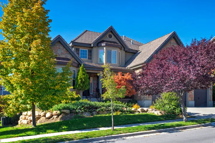 Stone and stucco exterior featuring a bay window with shutters, multiple gables, and a tiled roof