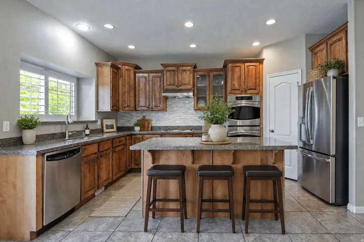 Kitchen featuring wood cabinetry, stainless steel appliances, granite countertops, and tile flooring