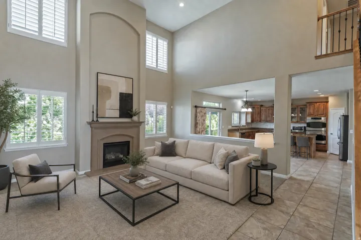 Two-story living area featuring a central fireplace with mantel, multiple windows with plantation shutters, and carpet flooring