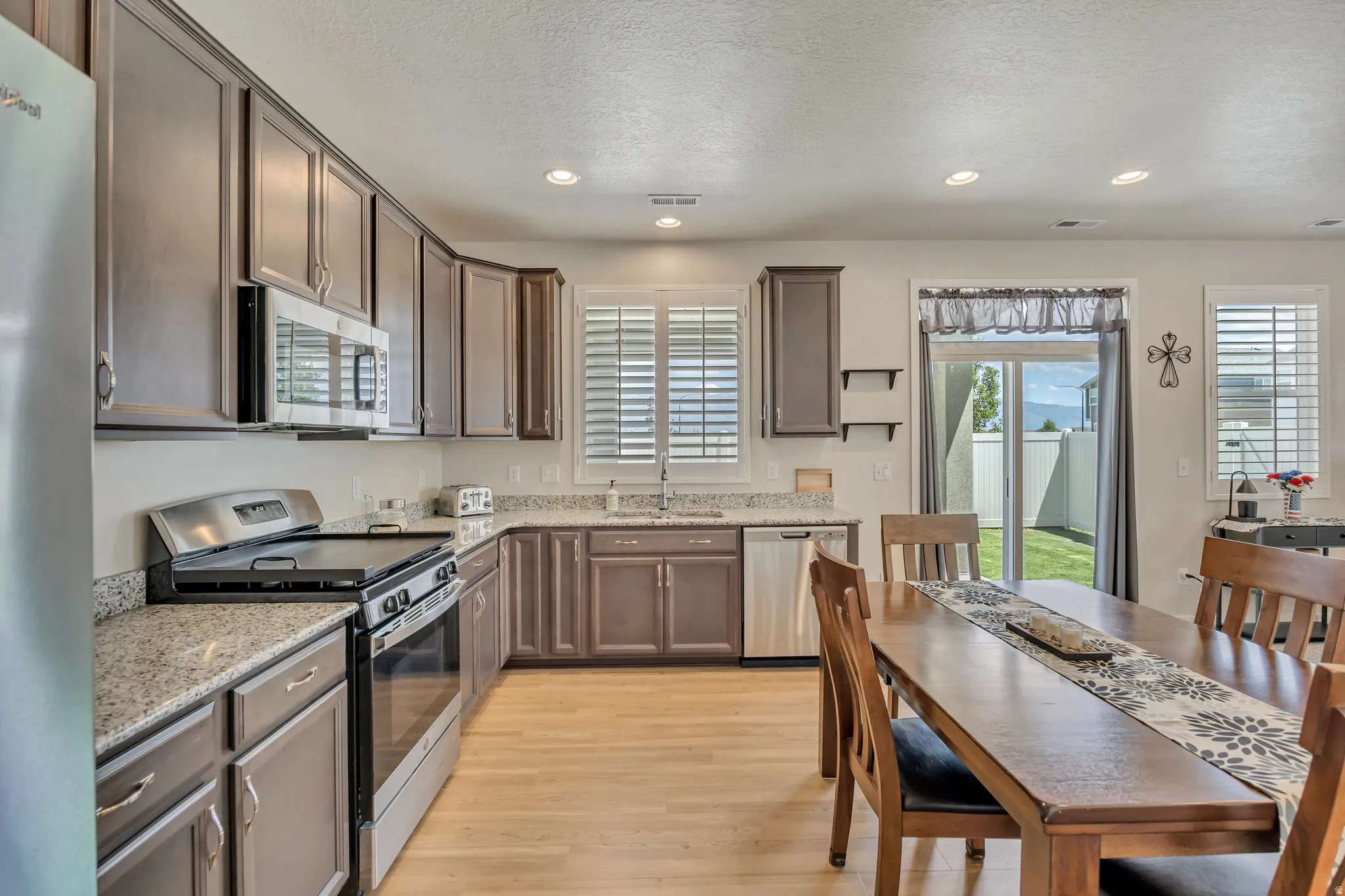Kitchen featuring stainless steel appliances, wood-finish flooring, granite countertops, and recessed lighting