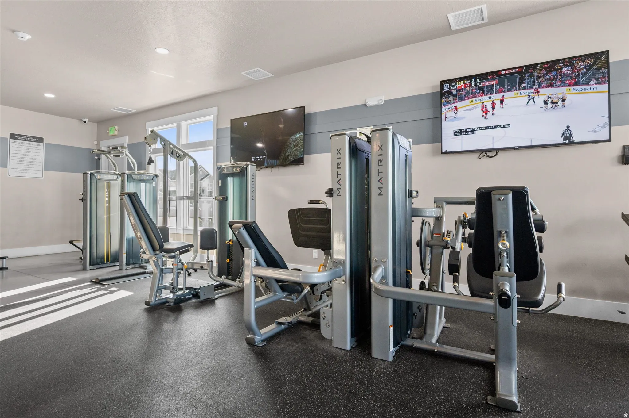 Fitness club house center featuring specialized exercise equipment, wall-mounted televisions, durable rubber flooring, and recessed lighting