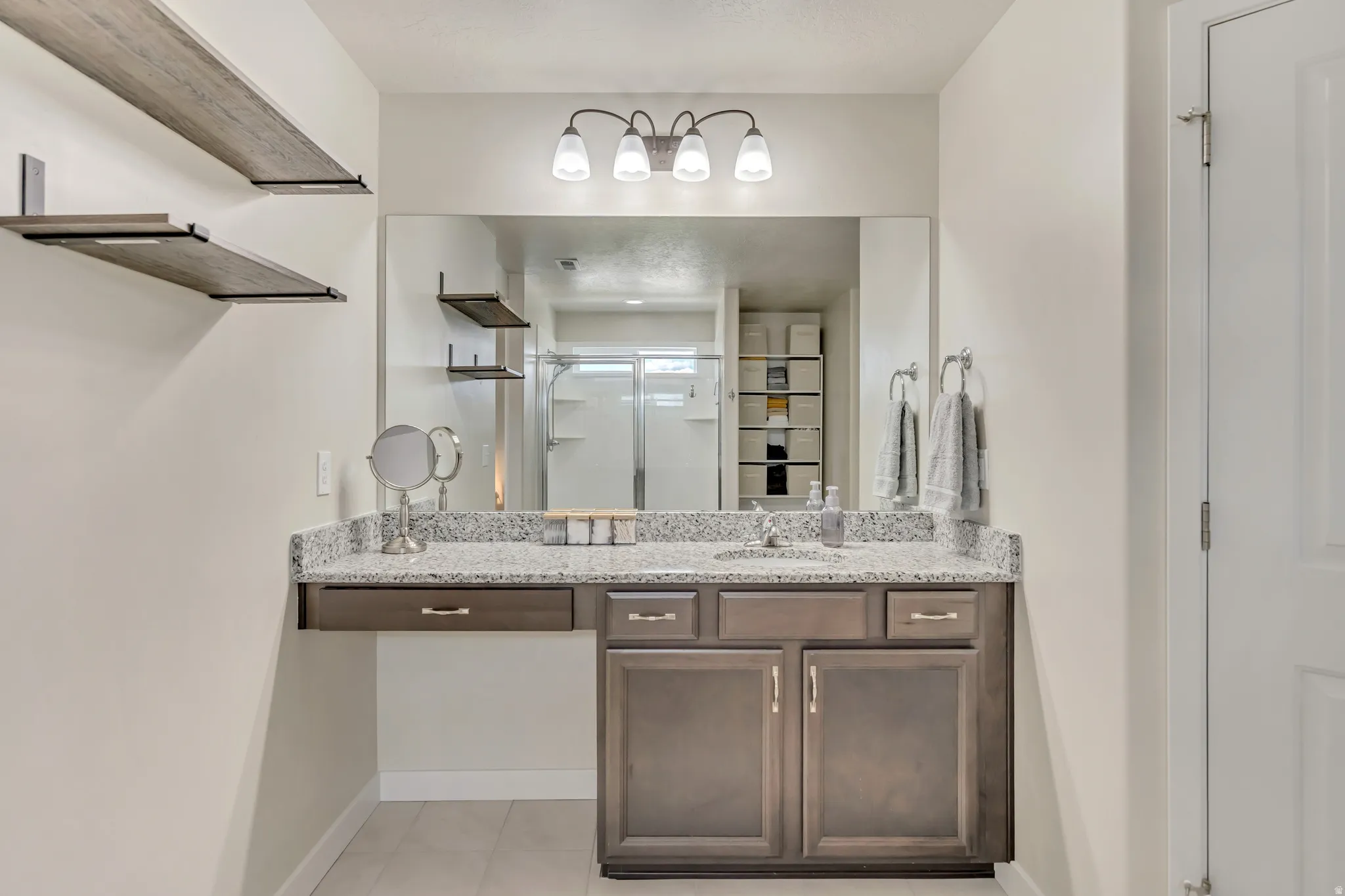 Vanity area featuring a spacious countertop with an integrated sink, dark wood-finish cabinetry, and a large wall-mounted mirror