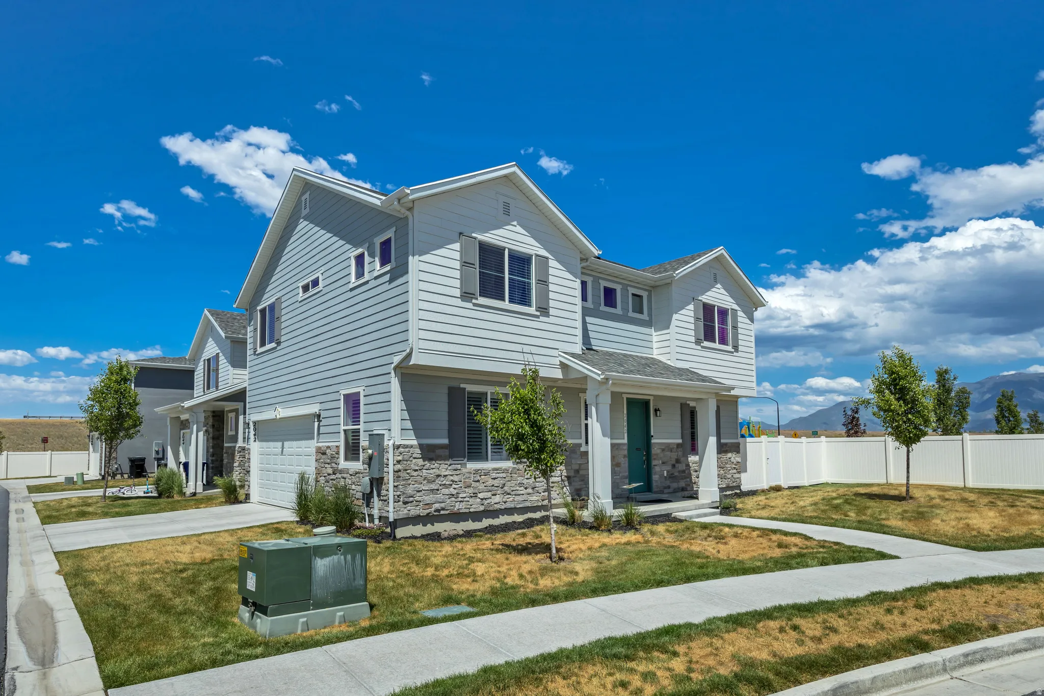 Contemporary two-story exterior featuring light gray siding and a stacked stone accent facade