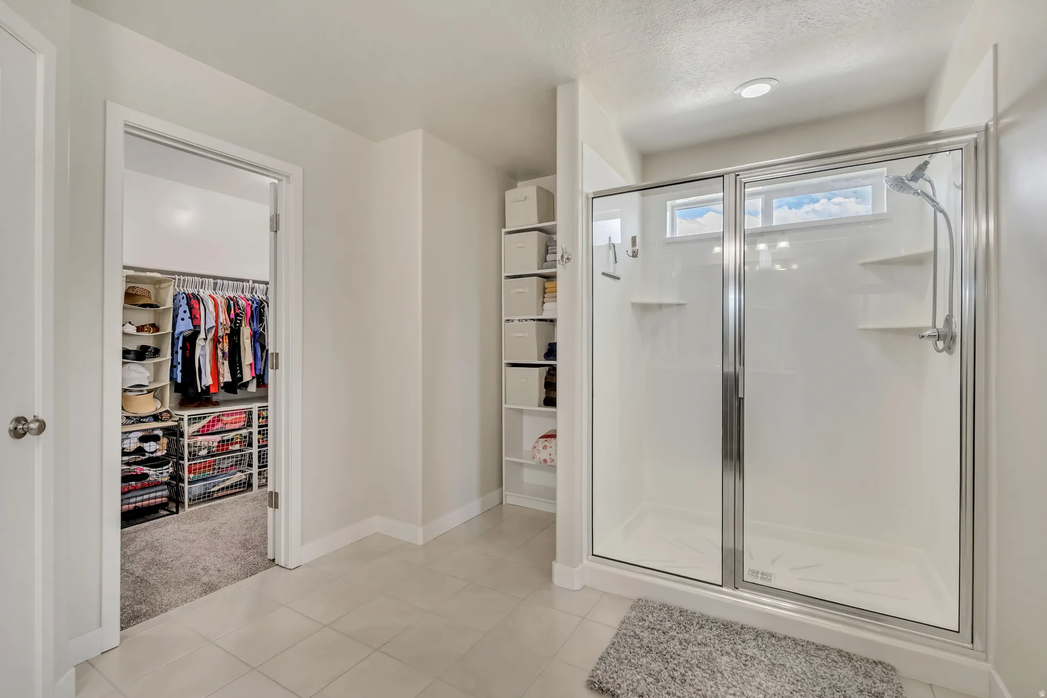 Glass-enclosed shower with transom window and wall-mounted shelving