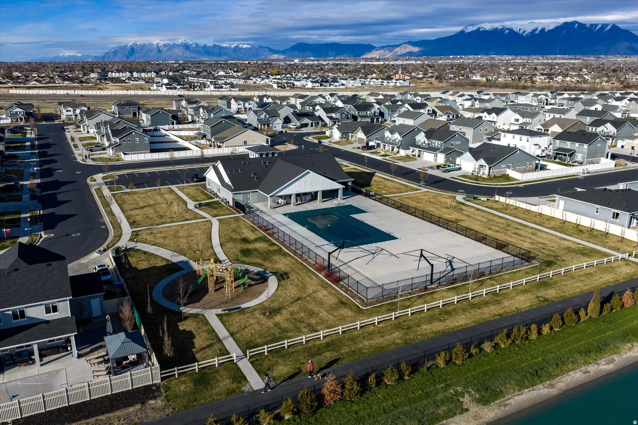 Community clubhouse with an outdoor pool, sports court, and playground