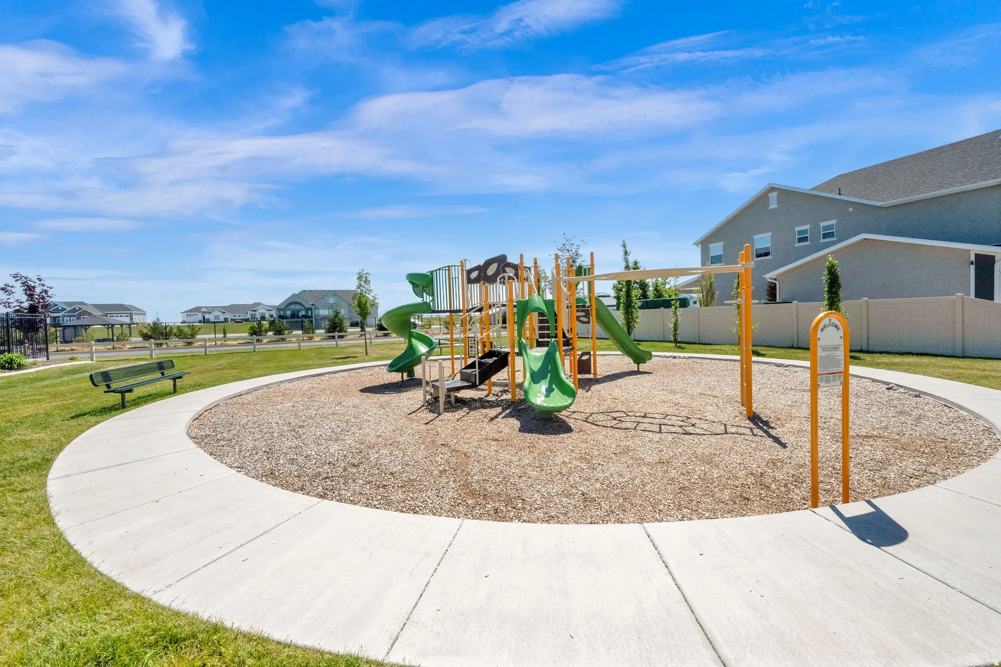 Community playground featuring green slides, yellow support structures, and a wood chip surface