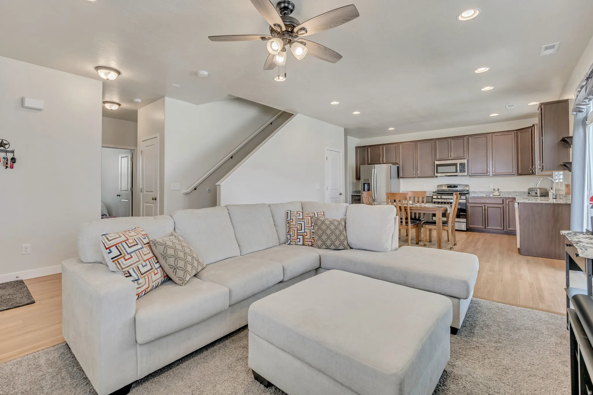 Open-concept living area featuring wood-finish flooring, recessed lighting, and a ceiling fan