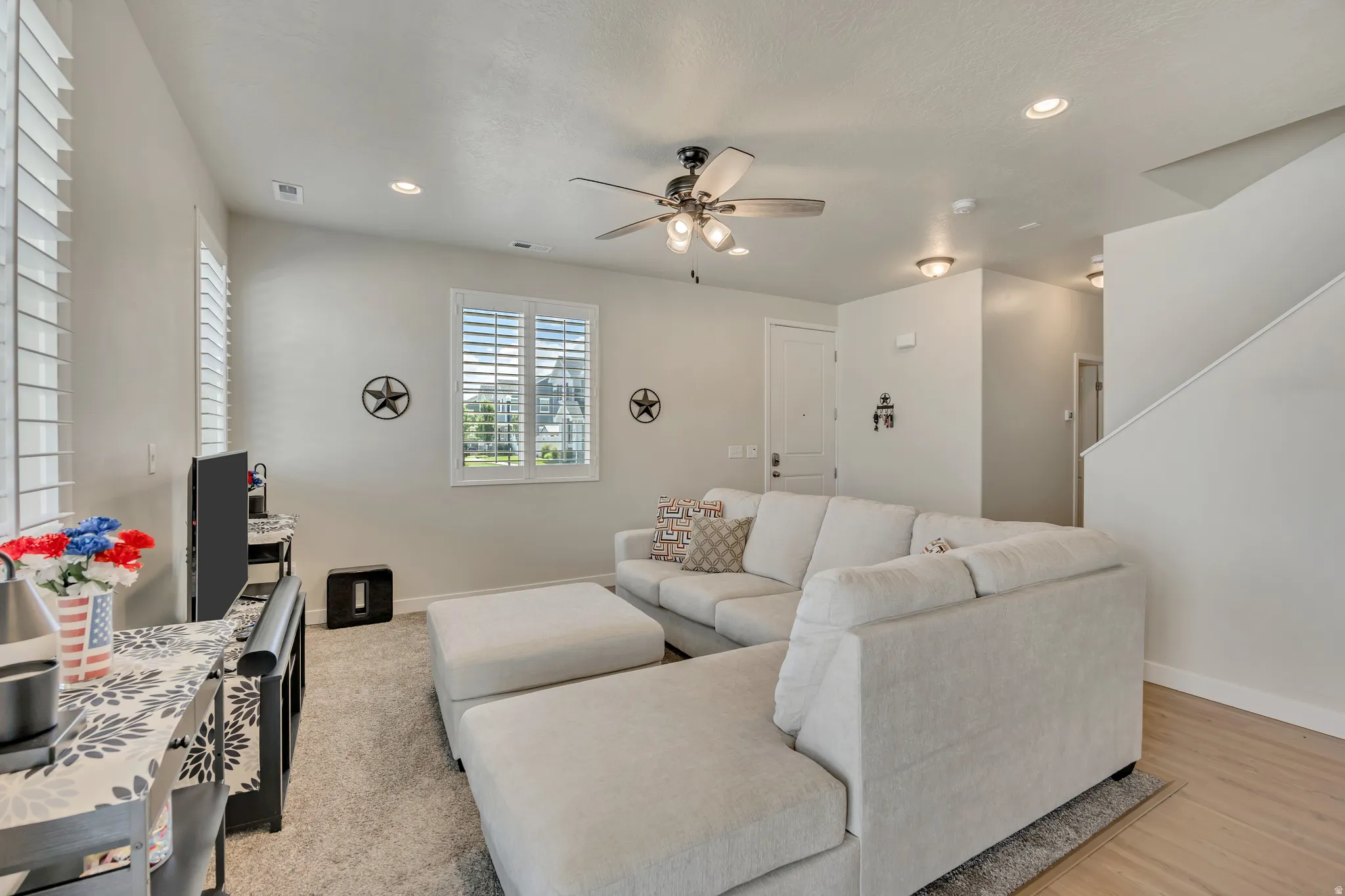 Living area featuring light-colored walls, recessed lighting, and a ceiling fan with integrated lighting