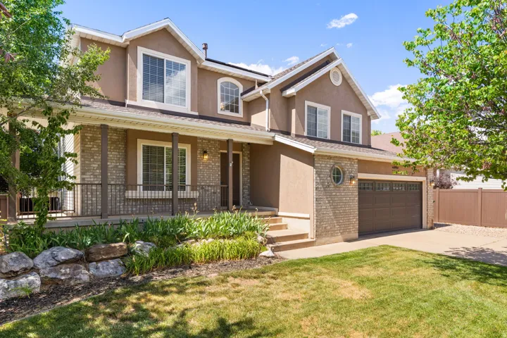 Beautiful multi-level home featuring a neutral brick and stucco exterior, covered front porch, and mature landscaping.