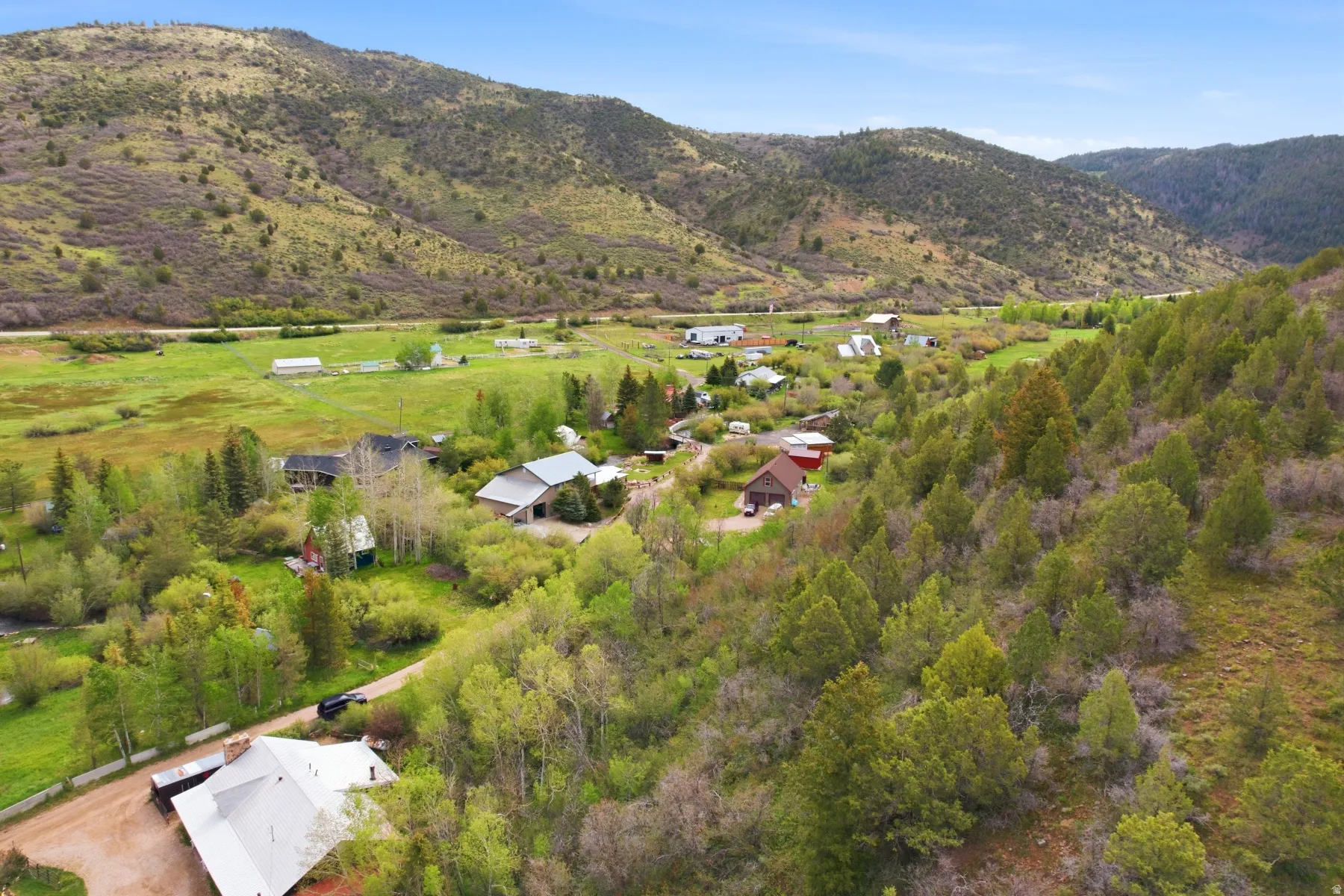 Rural landscape featuring multiple structures, extensive green acreage, and mountainous terrain