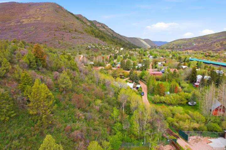 Expansive green hillsides frame a rural community featuring varied architectural styles and mature trees