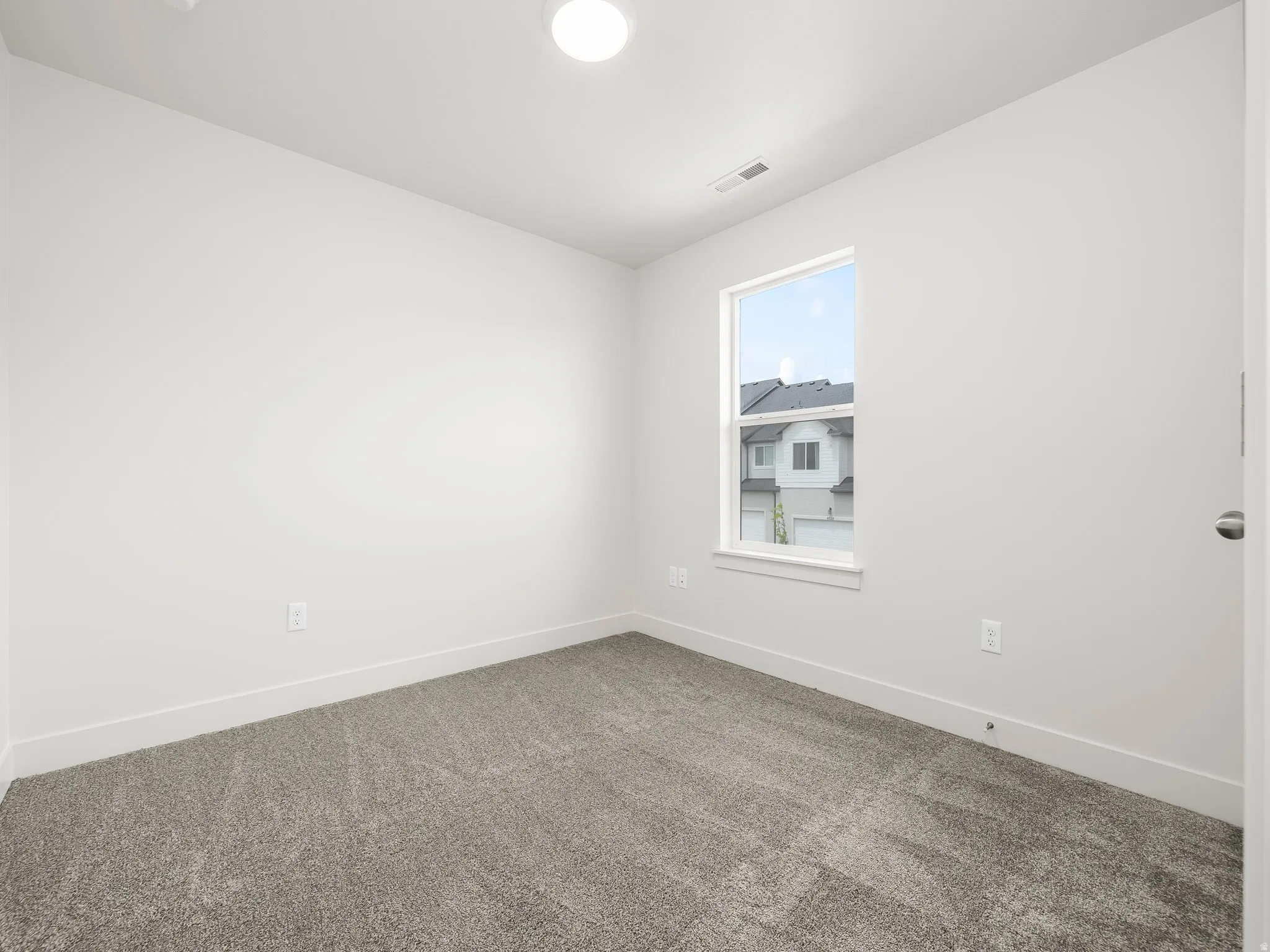 Light-filled room featuring neutral-toned carpeting, white walls, and a large window with white trim