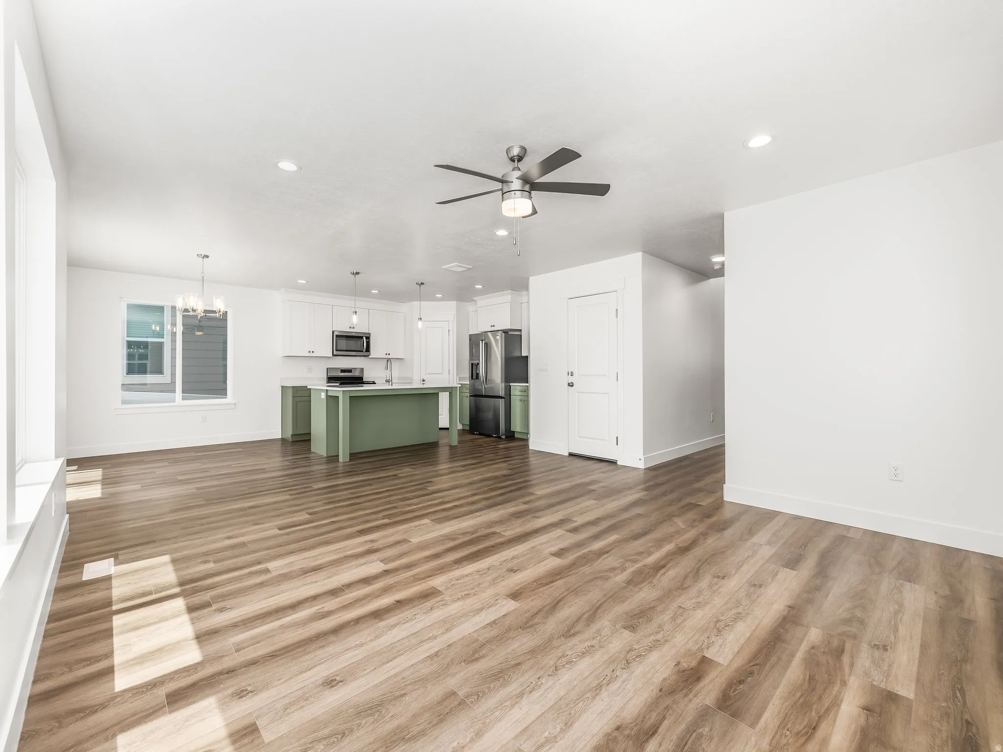 Open-concept living space featuring wood-finish flooring, a contemporary ceiling fan, and recessed lighting