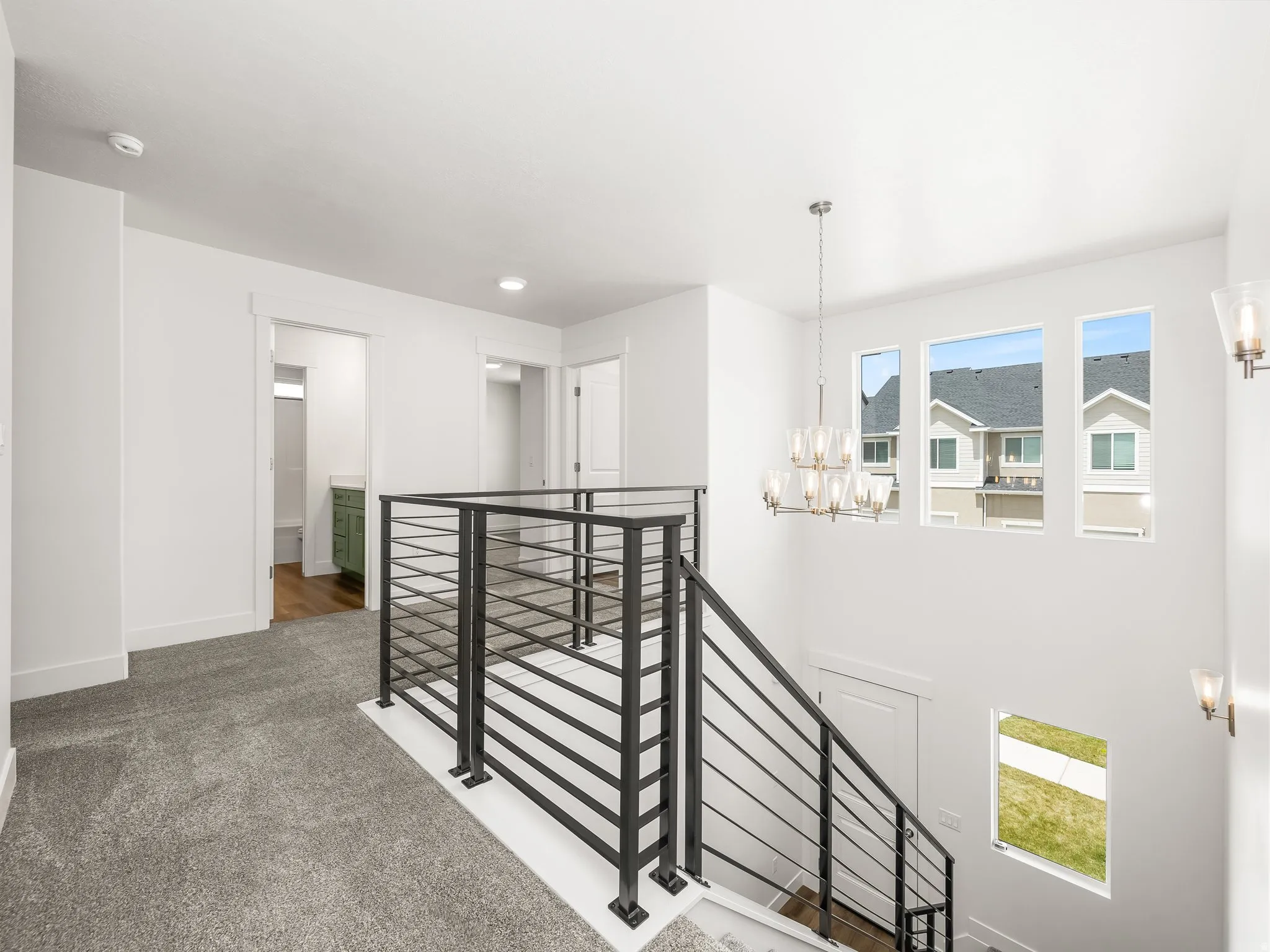 Upper-level landing featuring contemporary black metal horizontal stair railing, plush carpeting, and multiple windows