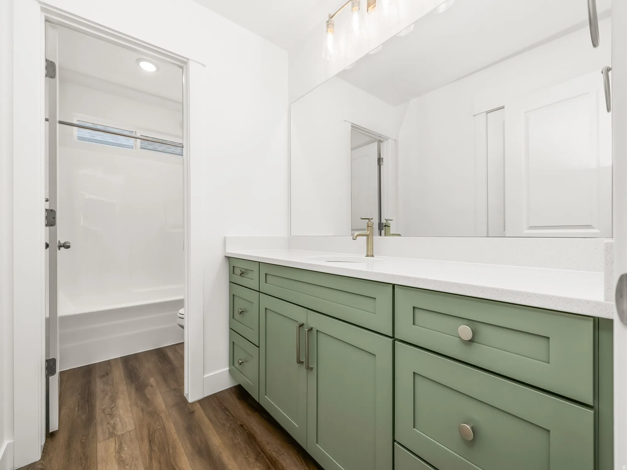 Bathroom vanity featuring a light green shaker-style cabinetry, a white countertop, and a rectangular undermount sink