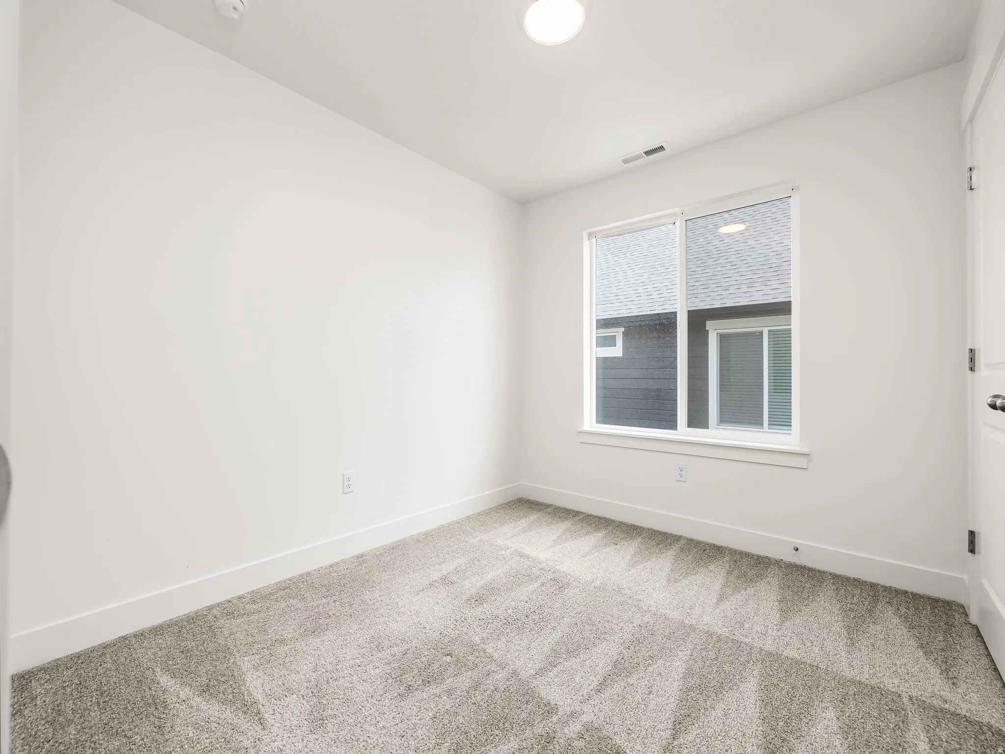 Room featuring light gray patterned carpeting, white walls, and a recessed ceiling light