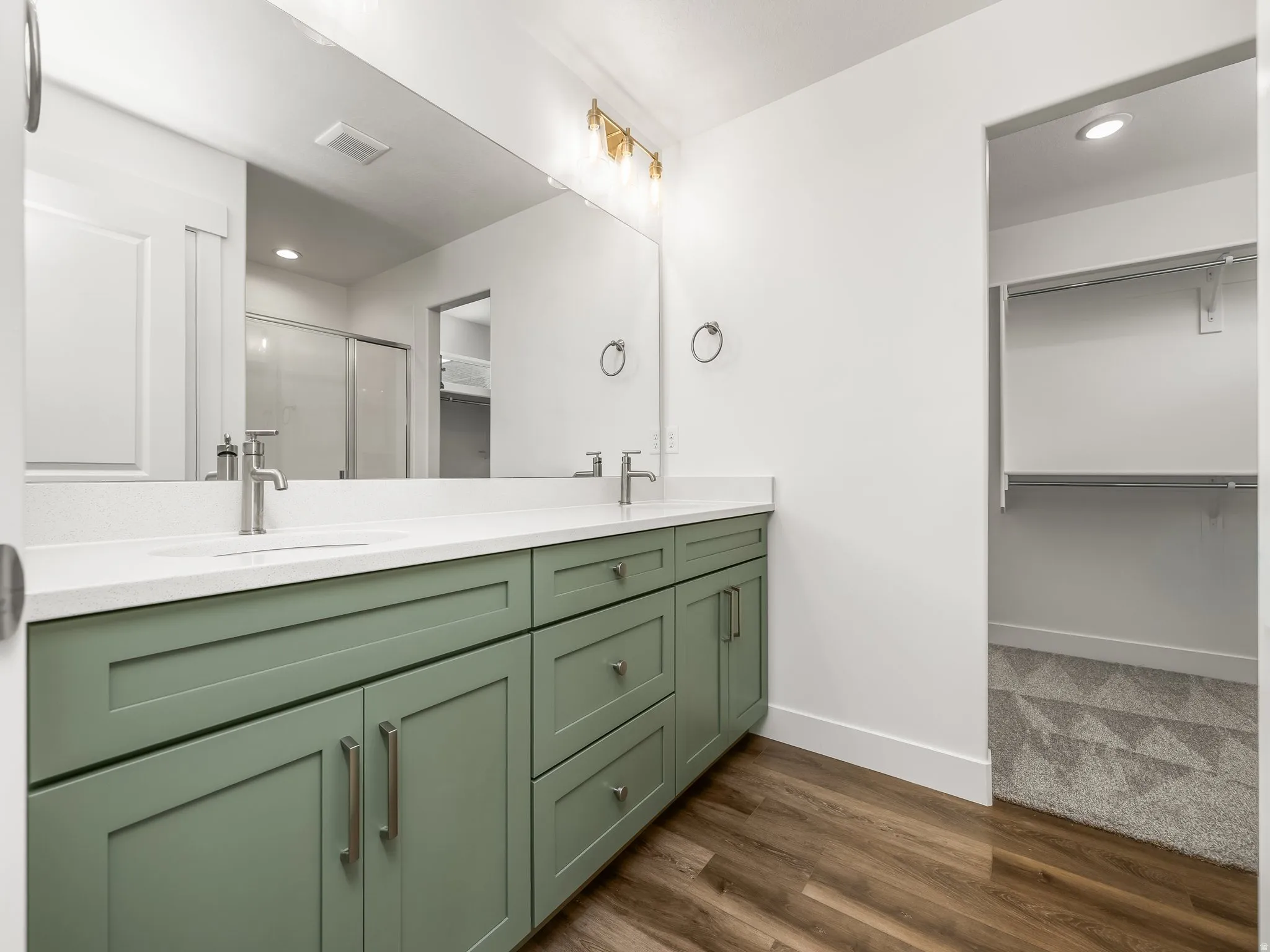 Double vanity with green cabinetry, white countertops, and brushed nickel hardware