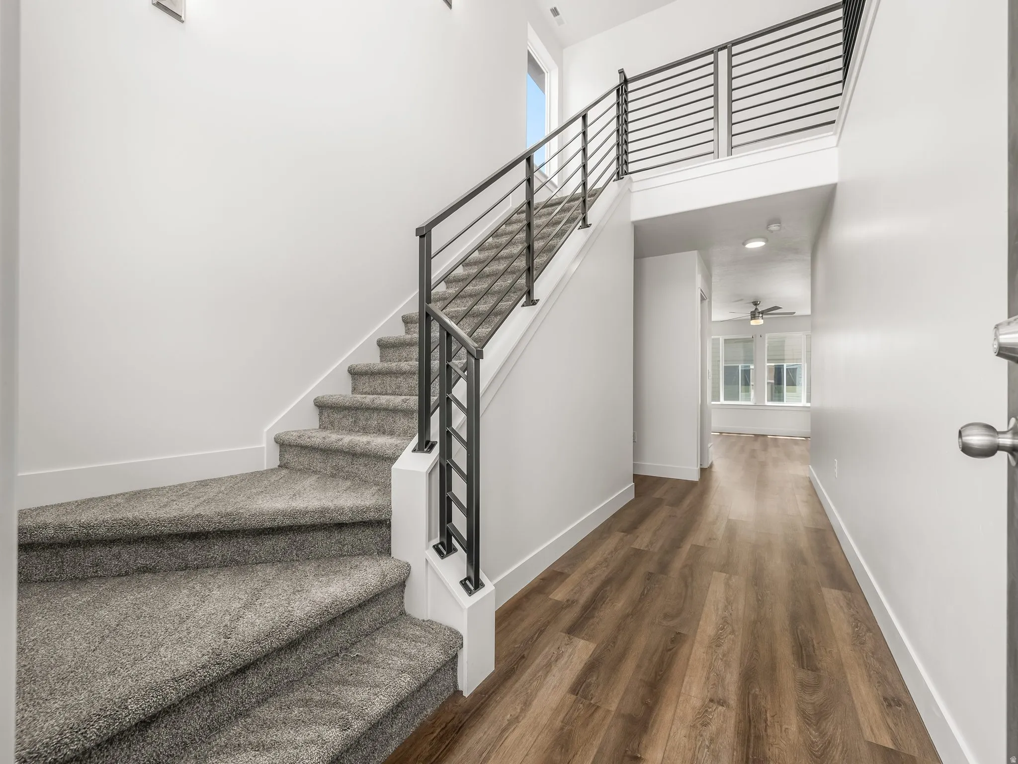 Carpeted staircase with contemporary metal railings and a wood-finish flooring entry