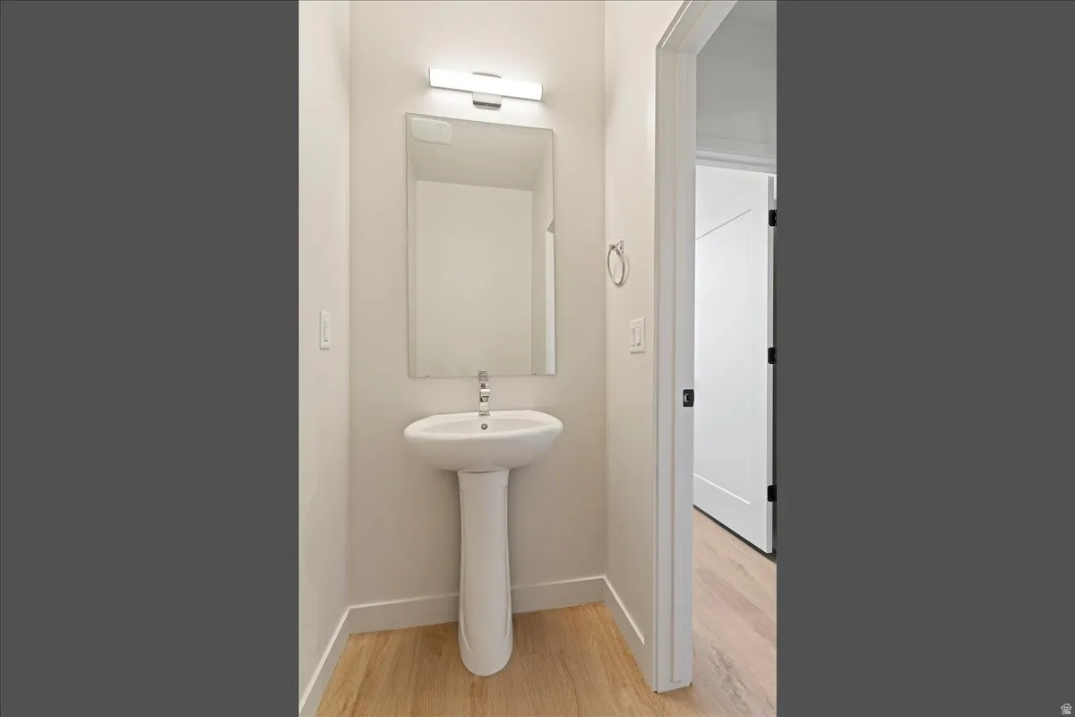 Pedestal sink with chrome faucet, rectangular wall mirror, and modern vanity light fixture