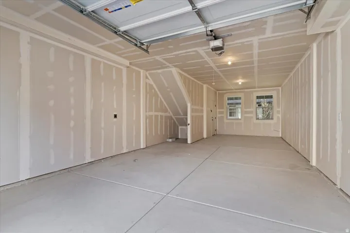 Spacious garage featuring a concrete floor, two windows providing natural light, and an overhead garage door mechanism