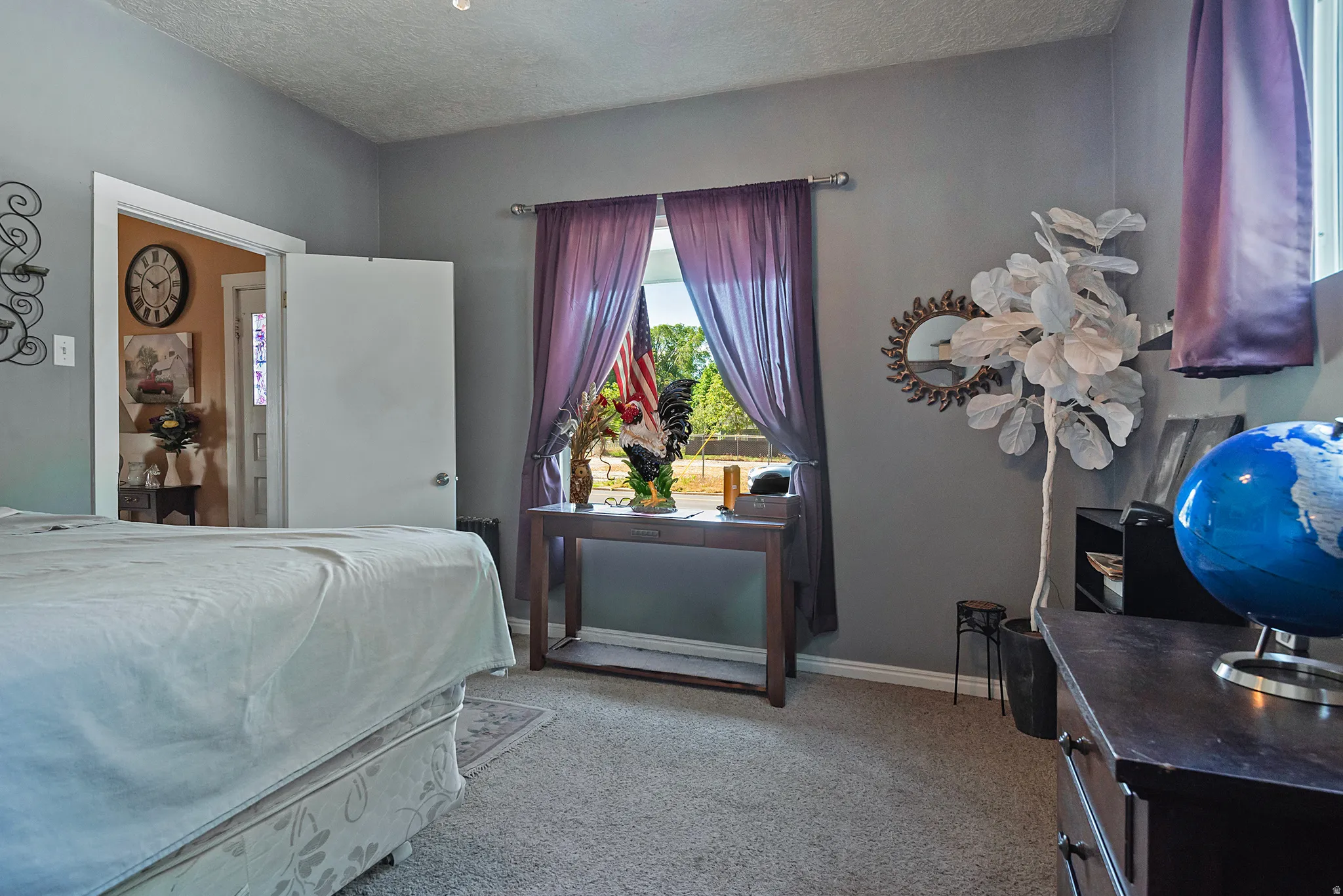 Carpeted room featuring a window with purple drapes, a white paneled door, and gray wall paint
