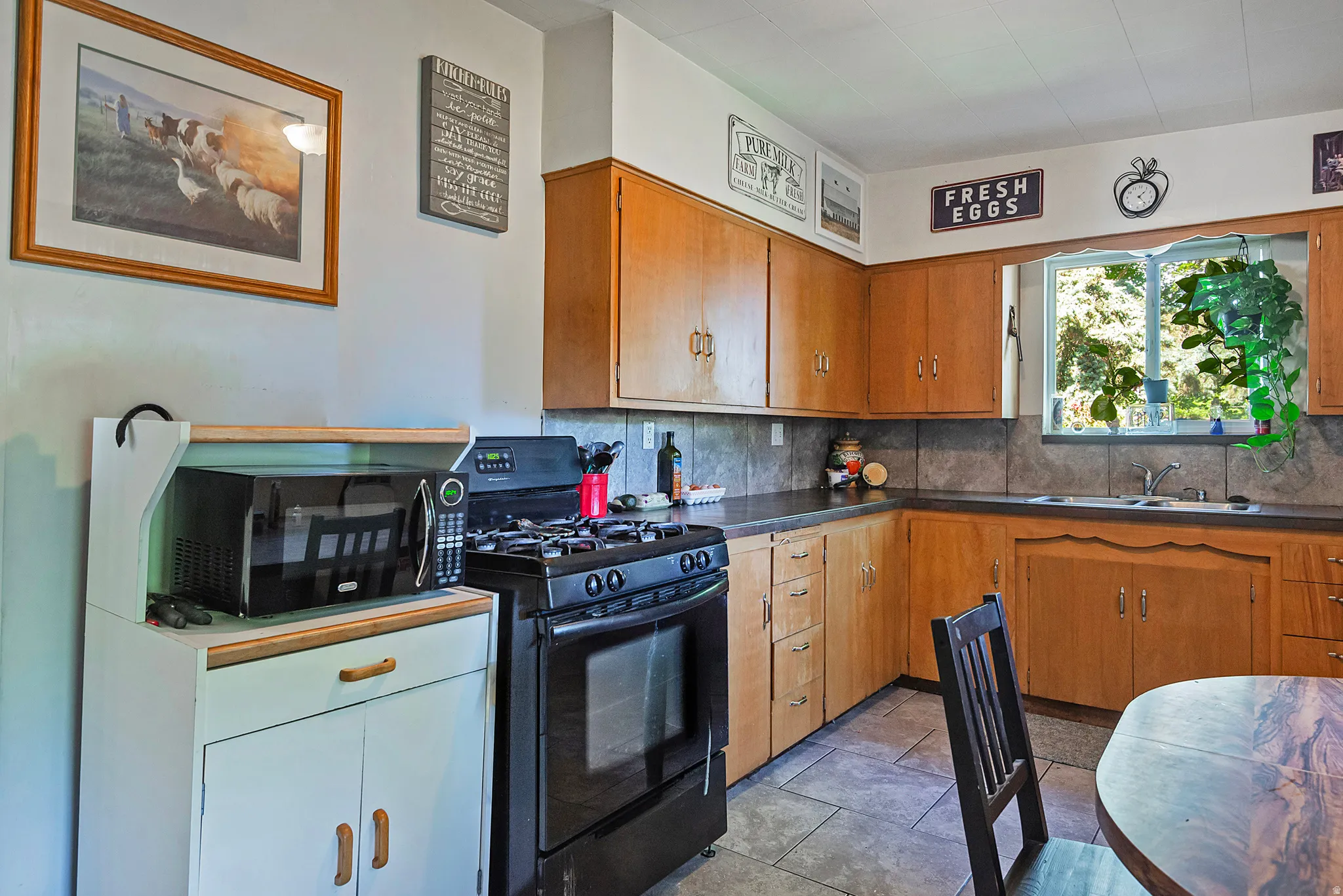 Kitchen featuring wood cabinetry, dark countertops, a tile backsplash, and tile flooring