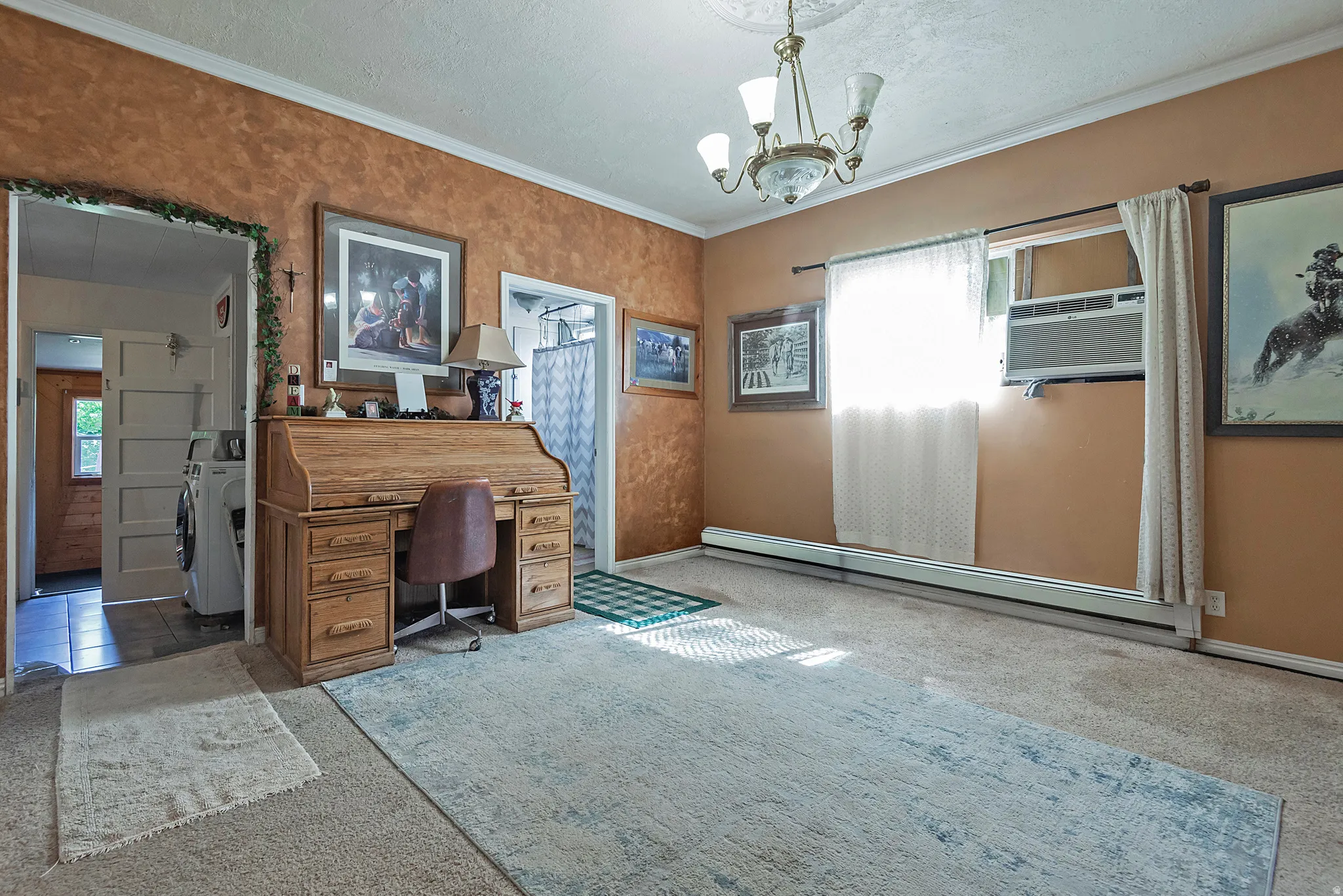 Spacious room featuring textured walls, crown molding, a ceiling-mounted chandelier, and a window with a built-in air conditioning unit