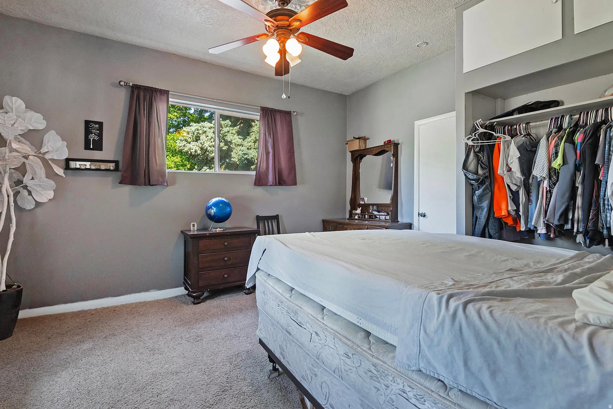 Carpeted room with a ceiling fan, a window, and a built-in closet with overhead storage